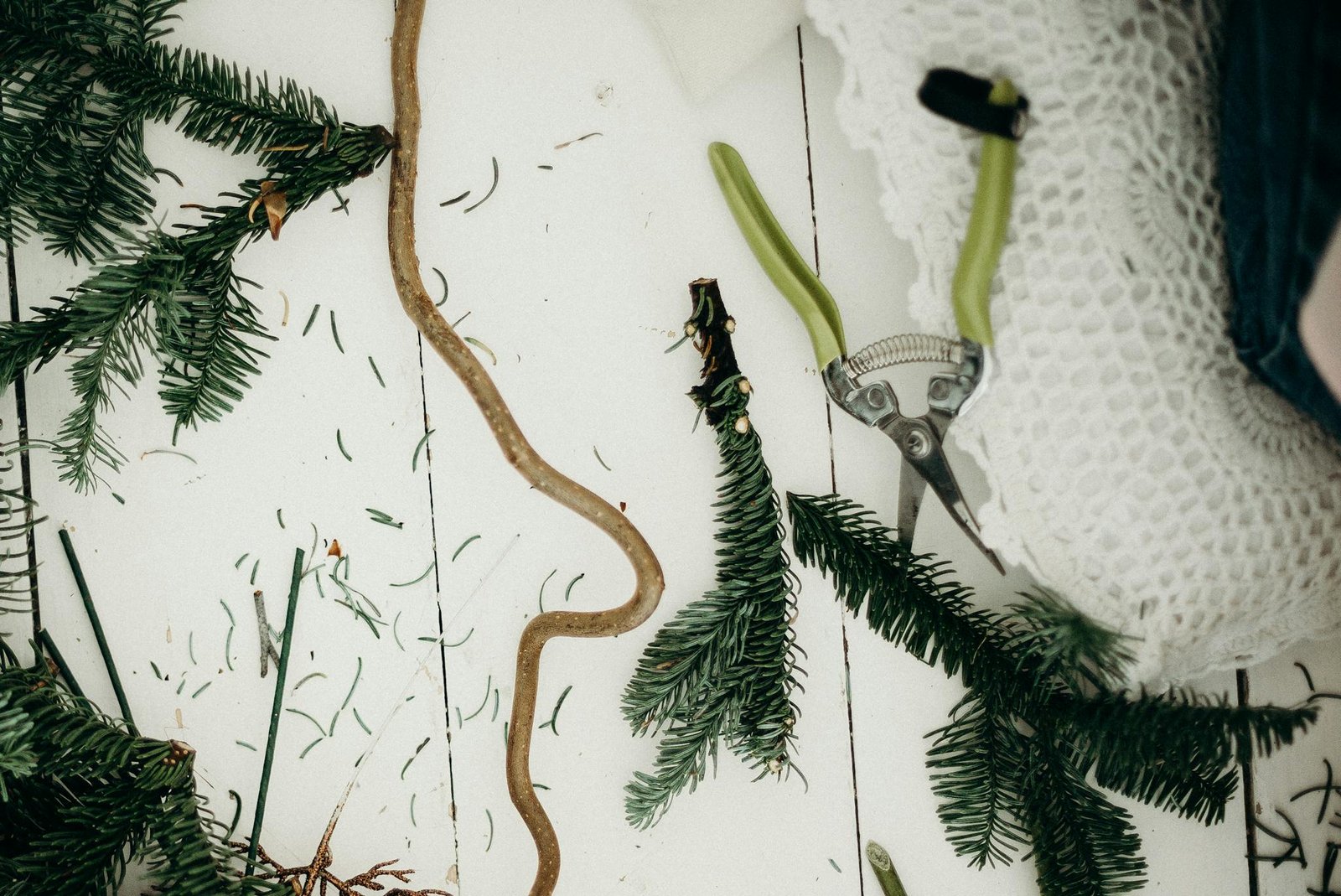 A creative flat lay of fir branches for Christmas decoration on a white wooden background.